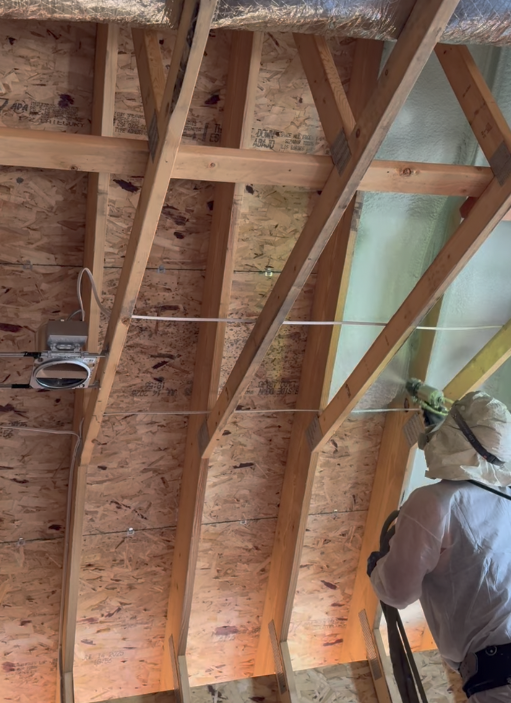 Worker applying spray foam insulation Fargo in a residential frame.